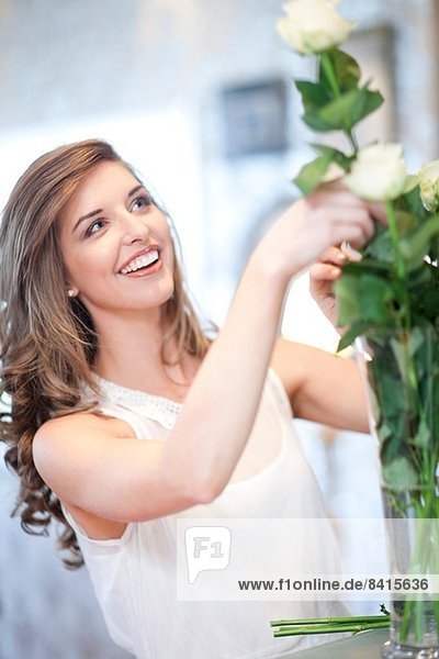 Junge Frau arrangiert Rosenstrauß in Vase