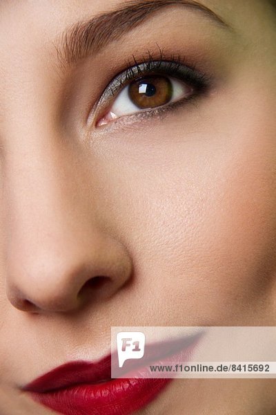Abgeschnittenes Studio-Porträt von Auge und Lippen einer jungen Frau