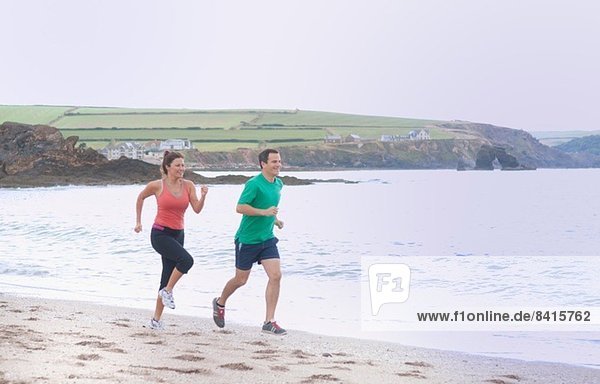 Couple running on beach  Thurlestone  Devon  UK