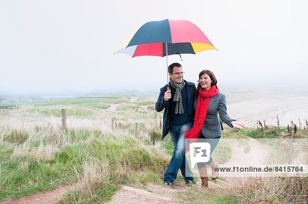 Paar auf Küstenwanderung mit Regenschirm  Thurlestone  Devon  UK