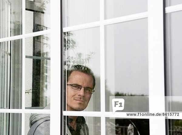 Porträt eines erwachsenen Mannes  der aus dem Fenster schaut.