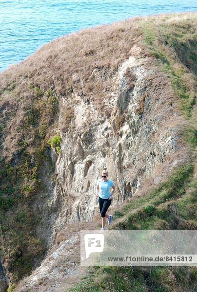 Mid adult woman jogging on coastal path  Thurlestone  Devon  UK