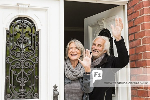 Seniorenpaar winkt vor der Haustür