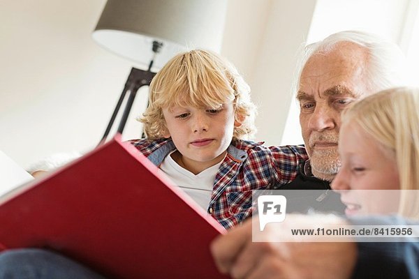 Großvater liest den Enkeln das Buch vor