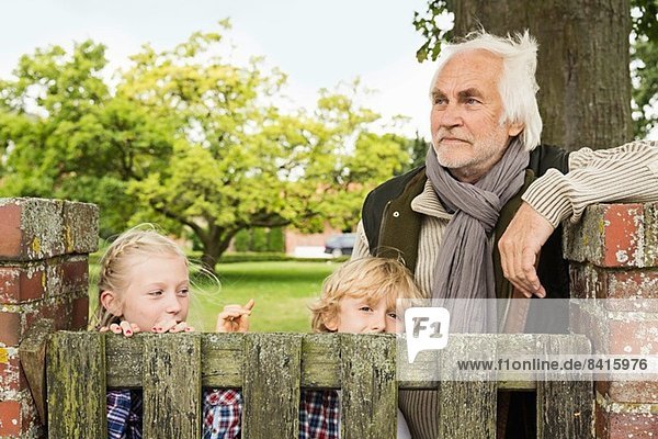 Großvater und Enkelkinder durch Holztor
