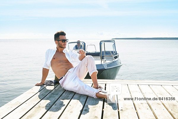 Young man sitting on pier  Gavle  Sweden
