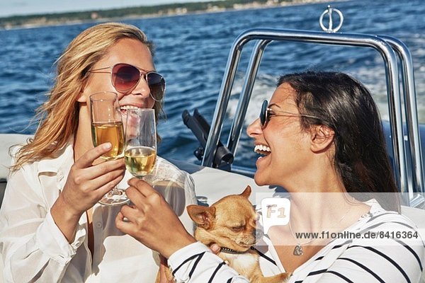 Zwei junge Frauen auf dem Boot beim Weintoasten