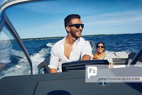 Junger Mann steuert Boot mit Frau im Hintergrund  Gavle  Schweden