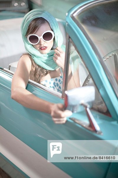 Frau im Kopftuch und weiße Sonnenbrille im Vintage Cabriolet