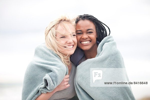 Gay couple wrapped in blanket on beach
