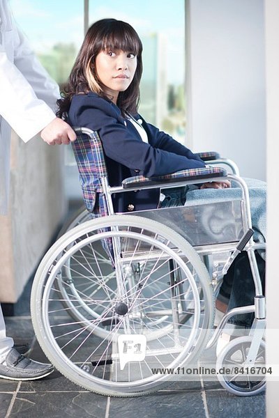 Frau im Rollstuhl unterstützt von einem Krankenpfleger