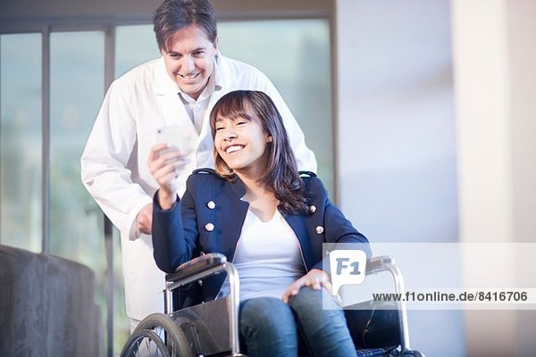 Frau im Rollstuhl unterstützt von einem Krankenpfleger
