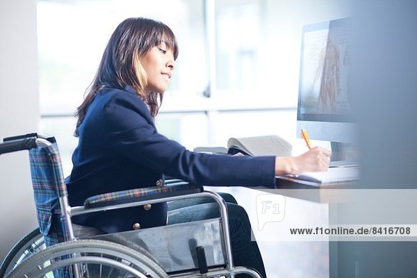 Frau im Rollstuhl schreibt Notizen