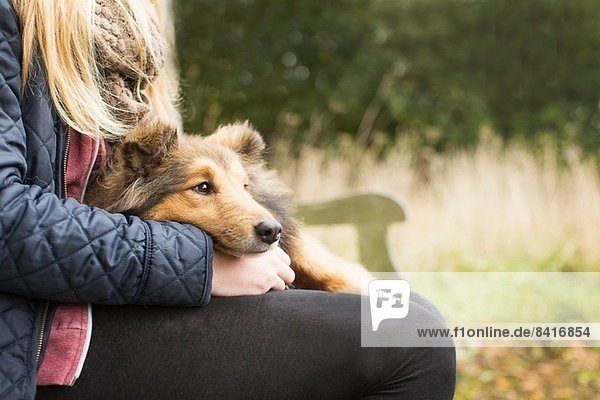 Detail eines Teenagermädchens  das auf einer Landbank mit Hund sitzt.