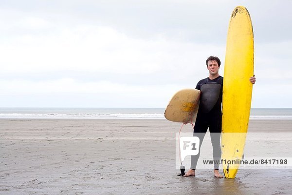 Porträt eines Mannes mit Surfbrettern am Strand