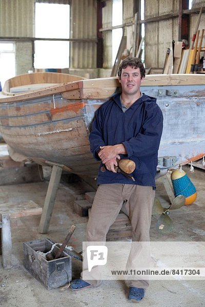 Porträt eines reifen Mannes mit Meißel in der Bootswerkstatt