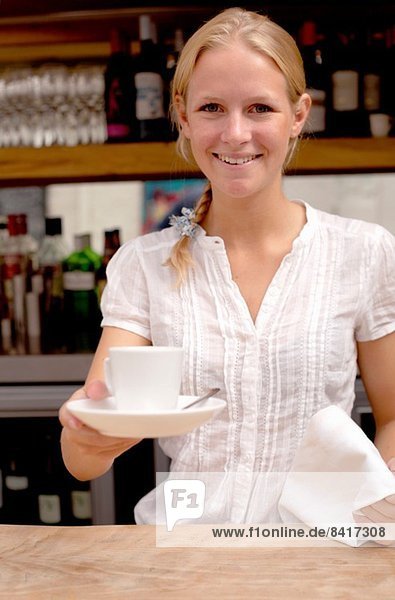 Porträt einer jungen Kellnerin mit Kaffee an der Küchentheke