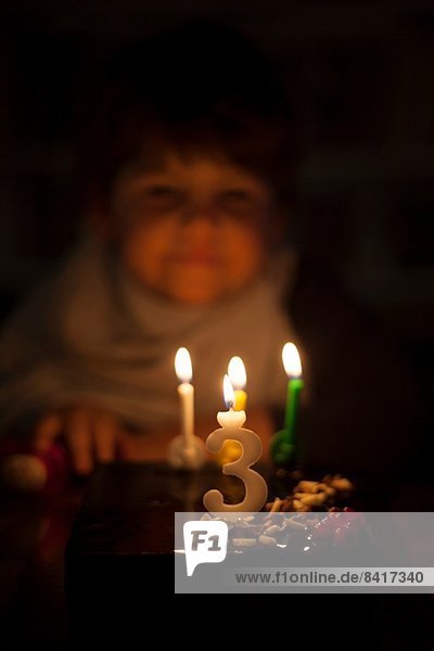 Candlelit male toddler looking at birthday cake