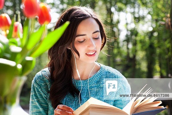Young woman with earphones reading book
