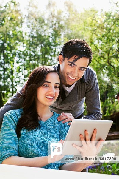 Portrait of young couple with digital tablet in garden