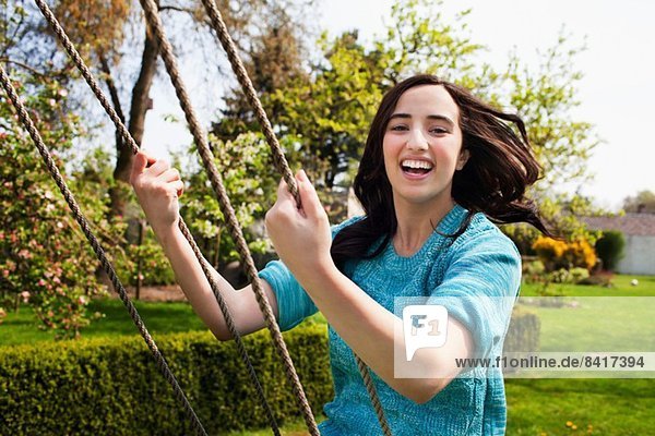Portrait of young woman enjoying garden swing