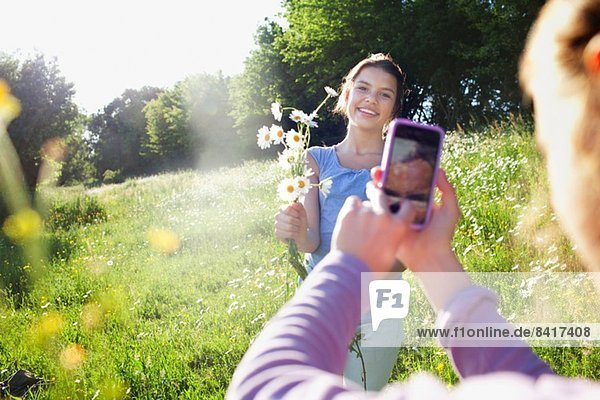Mädchen beim Fotografieren von Mädchen beim Blumenpflücken