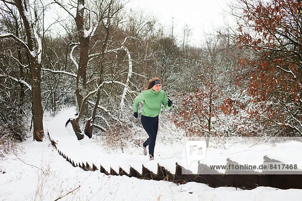 Läuferin  die im Winter die schneebedeckte Treppe hinaufsteigt