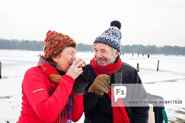 Couple having hot drink in snow