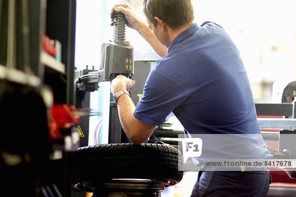 Mechanic repairing wheel in workshop