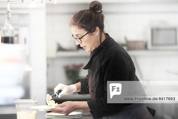Frau  die in der Restaurantküche arbeitet und Mahlzeiten serviert