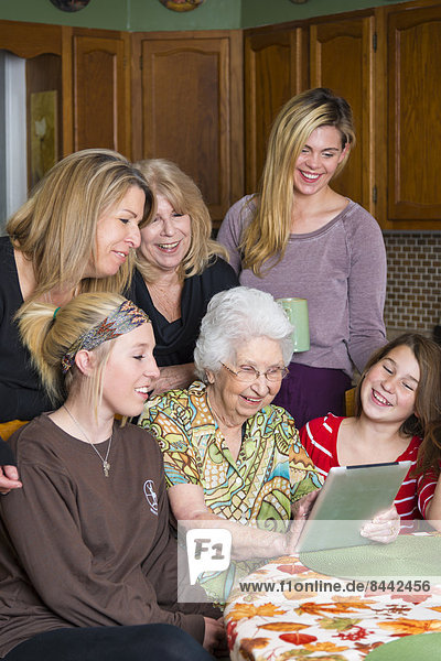 Ältere Frau mit Tablet-Computer inmitten ihrer Familie