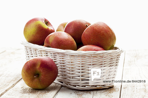 Apples (Malus) in white basket on wooden table