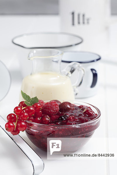Red berry compote and vanilla sauce on wooden table