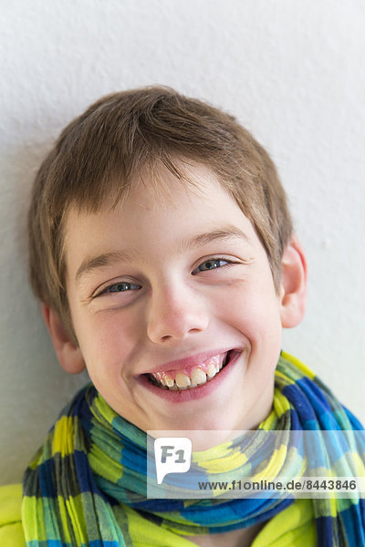 Porträt eines lächelnden Jungen mit Kapuzenjacke und Schal