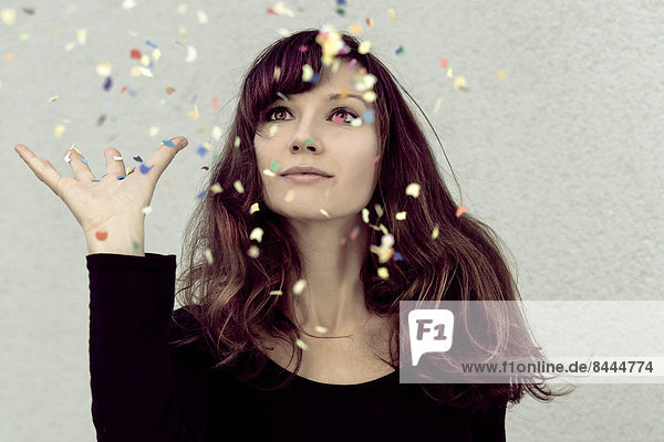 Young woman looking at confetti in the air