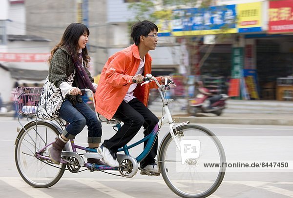 Couple on a tandem bicycle in Yangshuo street  China