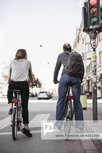 Rückansicht des Paares mit auf Signale wartenden Fahrrädern an der Stadtstraße