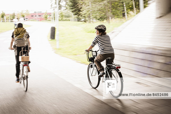 Verschwommene Bewegung von Vater und Tochter beim Fahrradfahren auf der Straße