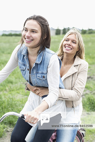 Happy female friends enjoying bicycle ride on country road