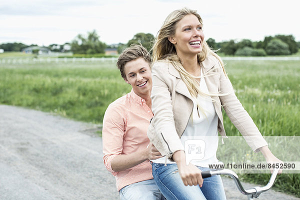 Happy young couple enjoying bicycle ride at countryside