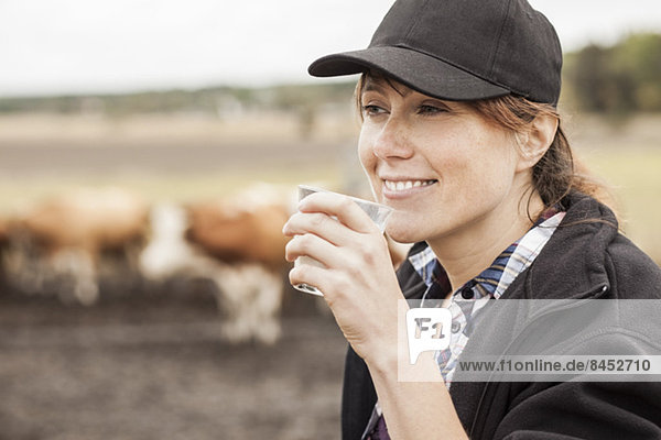 Mittlere erwachsene Bäuerin trinkt Milch auf dem Bauernhof