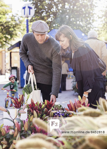 Junges Paar  das auf dem Markt Blumen auswählt