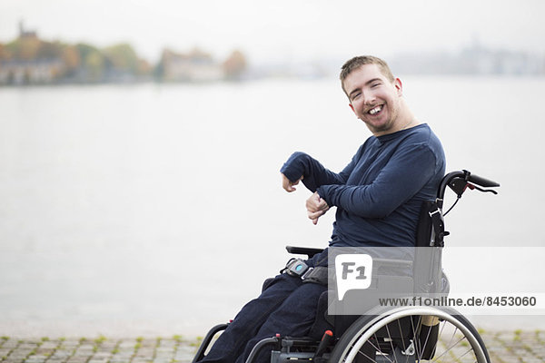 Porträt eines glücklichen Mannes mit zerebraler Lähmung im Rollstuhl am See