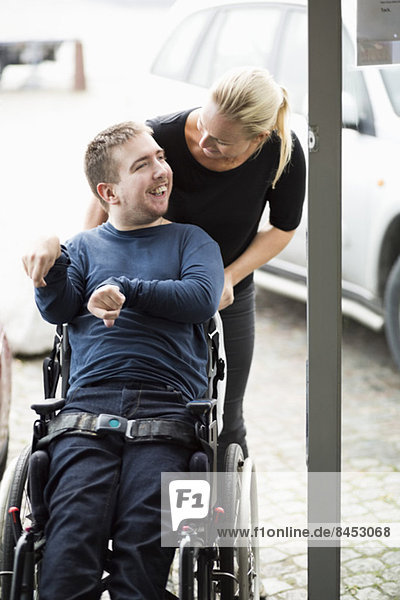 Hausmeister im Gespräch mit behinderten Menschen im Rollstuhl im Freien
