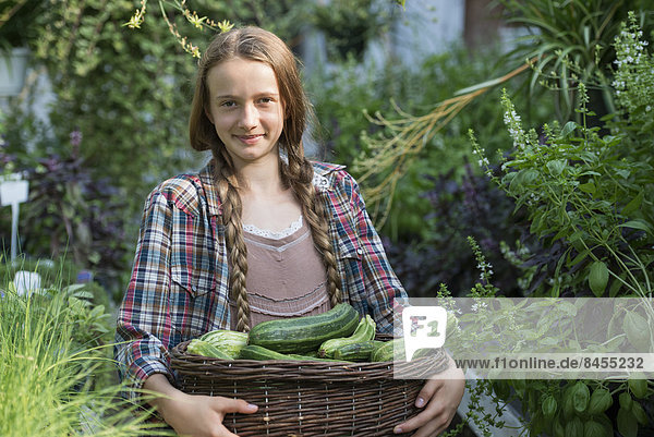 Sommer auf einem Biobauernhof. Ein Mädchen hält einen Korb mit frischen Kürbissen.