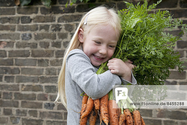 Ein junges Mädchen hält einen großen Karottenstrauß in der Hand.