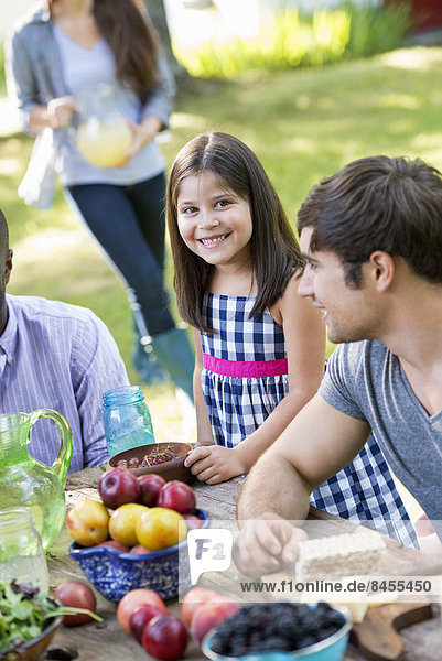 Erwachsene und Kinder um einen Tisch bei einer Party in einem Garten.