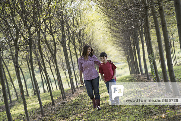 A woman and a child walking down an avenue of trees.