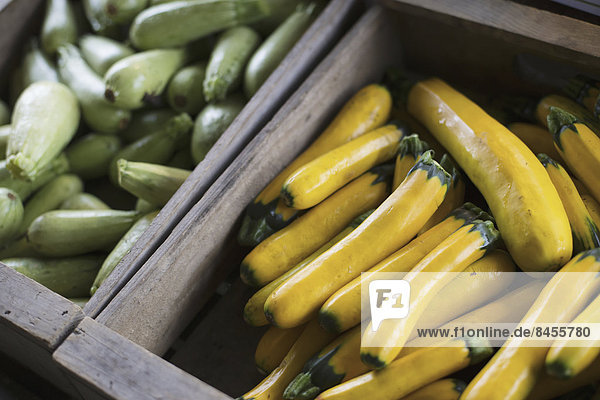 An organic farm stand. Boxes of yellow and green courgettes.