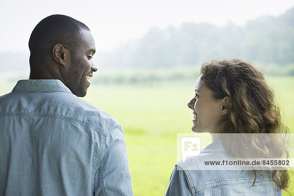 Ein junger Mann und eine junge Frau  ein Paar nebeneinander stehend. Sie sehen einander an.